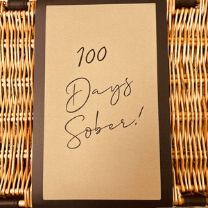 Wicker gift hamper with an "100 days sober" message on its sleeve