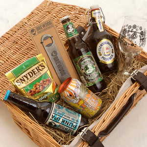A Father's Day gift hamper containing various craft beers, a Brewdog metal bottle opener, and beer-themed snacks presented in a wicker basket.