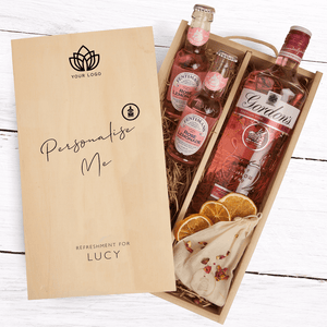 A personalised corporate gift box containing bottles of gin and tonic, with a personalised message card displaying the name 'Lucy'. The box is labeled with a placeholder for a company logo.