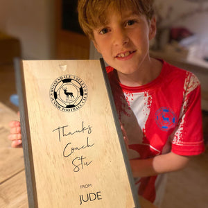 Image of little boy holding gift box for coach