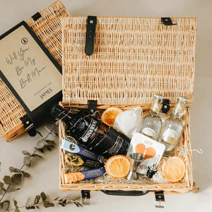 A  best man gift hamper containing gin, tonic, and snacks, with a sleeve reading 'Will You be My Best Man?'