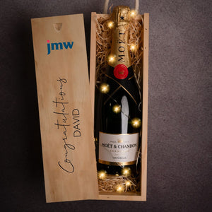 Moet Champagne lit with fairy lights in a wooden gift box featuring a company logo and the words 'Congratulations David' on the front.